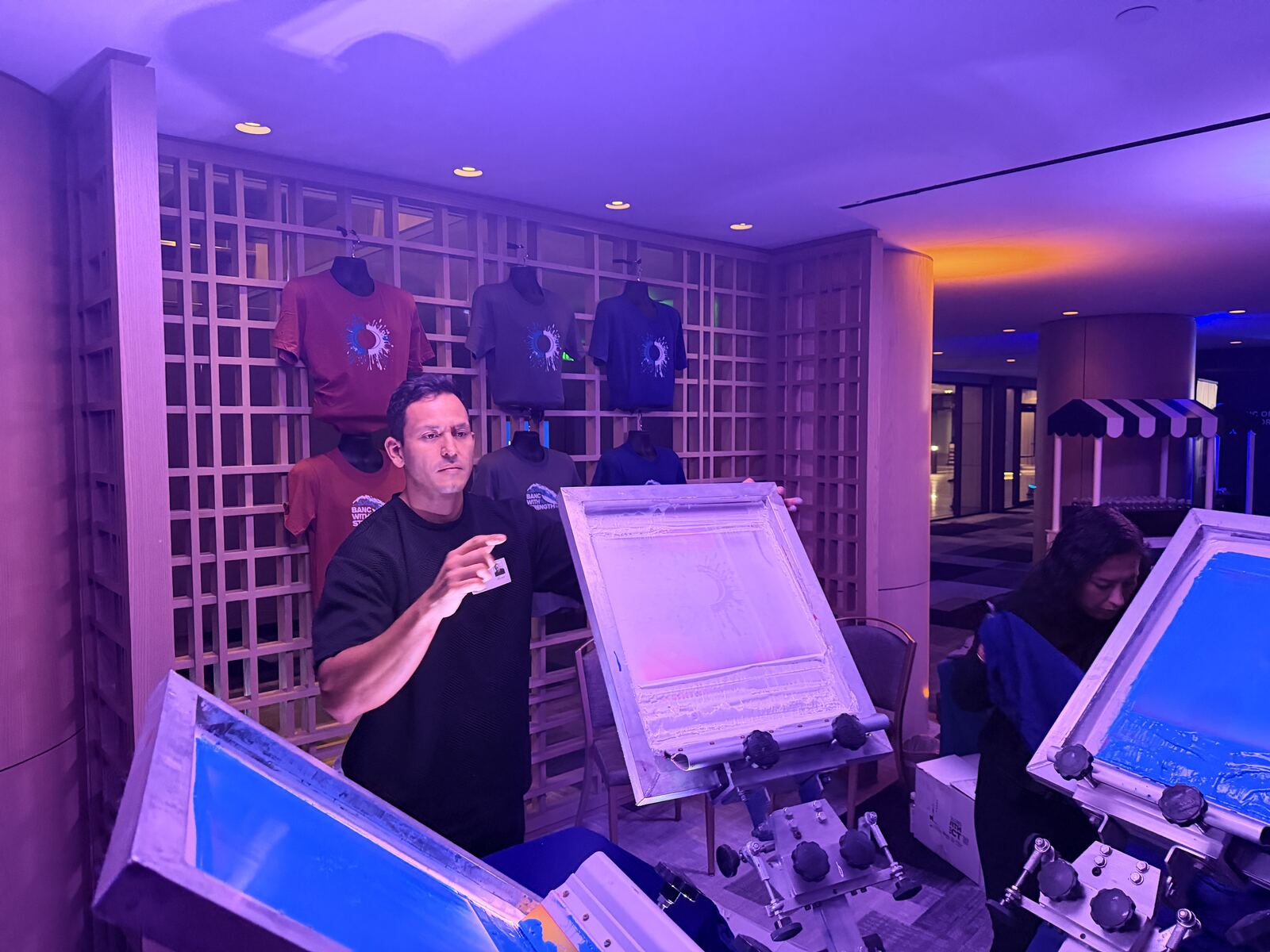 Professional display showcasing DTF-printed apparel with vibrant designs under dramatic purple and blue lighting at an event booth